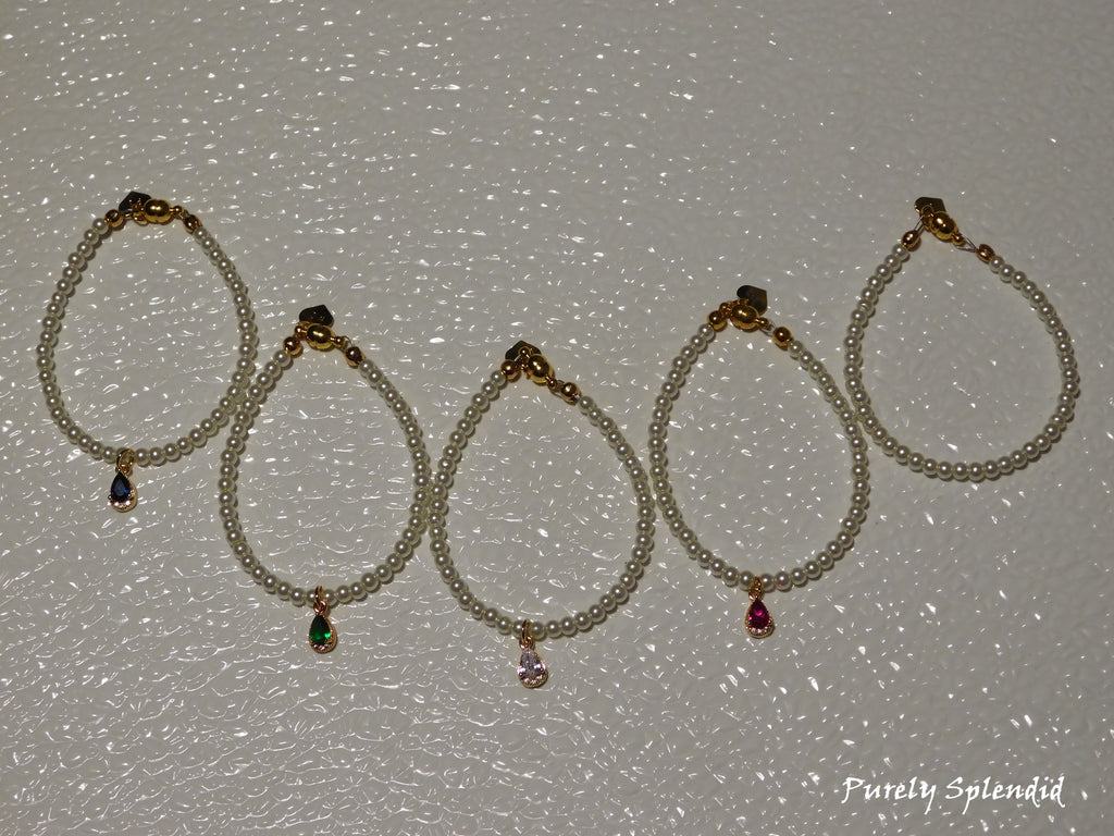 five Classic Pearl Necklaces one with a blue center pendant, one with a green, one with a clear one with a pink and the simple pearl stand without a pendant