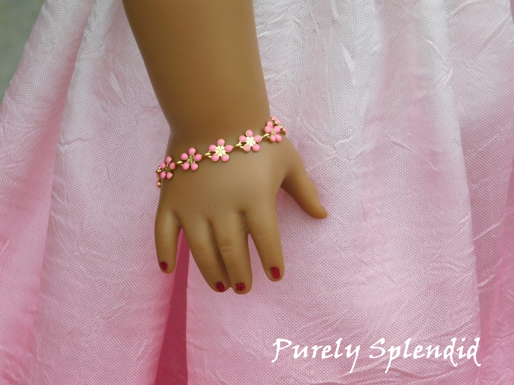 18 in doll shown wearing a Dainty Pink Flower Bracelet made up of 10 small pink daisy like flowers