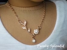 Load image into Gallery viewer, unique asymmetrical floral necklace in rose gold. The focal point has Sparkling flower on one side with three sparkling leaves on the other side, leading to a sparkling crystal. Shown on an 18 inch doll
