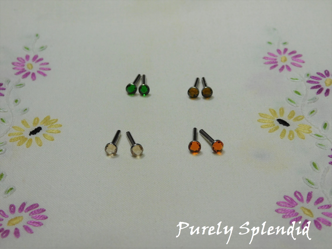 Set of four Earthy Crystal Stud Earrings, Fern Green, Honey, Smoked Topaz and Tangerine on a white floral background