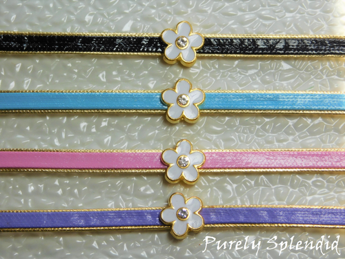 Four pretty Flower Choker Necklaces on a white background - black, blue, pink and purple leather like choker with a gold rimmed white enamel flower with sparkling center