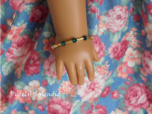 three green colored crystals are highlighted on this gold bangle bracelet