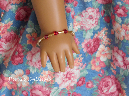 three red crystals highlighted on a gold colored bangle bracelet