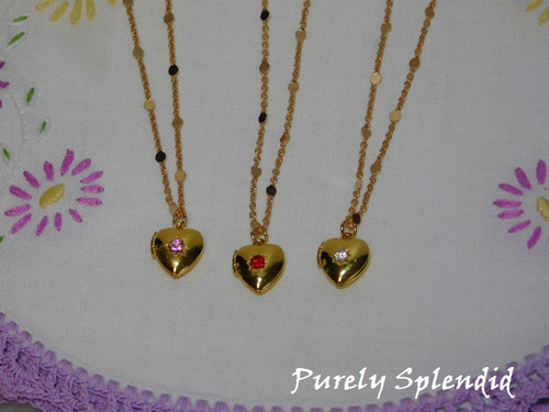 Three gold colored Heart Locket Necklace each hanging from a pretty gold colored chain. Each locket had a colored rhinestone center stone- one pink, one red and one crystal