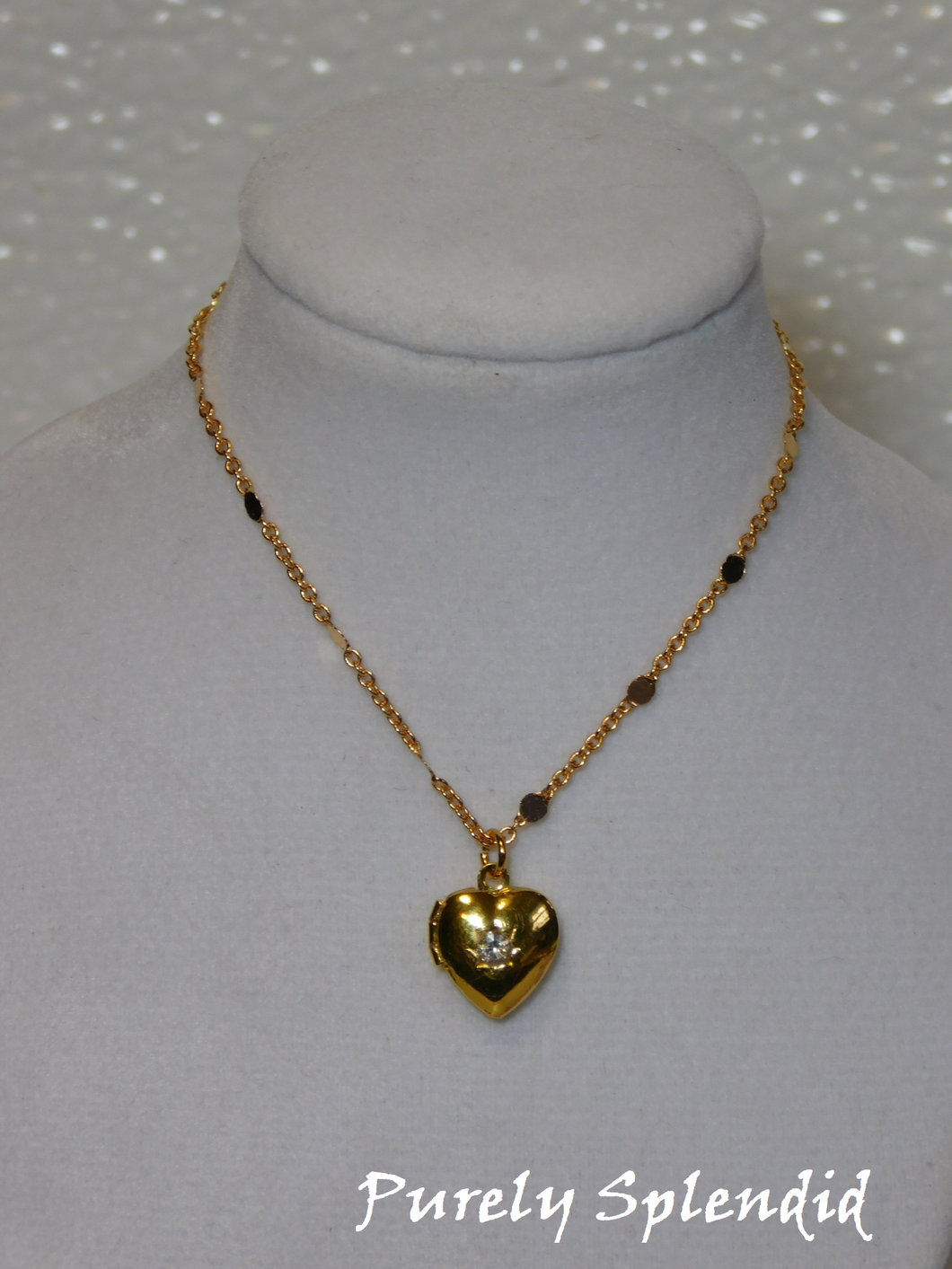 gold heart locket with a clear center crystal hanging from a pretty gold chain