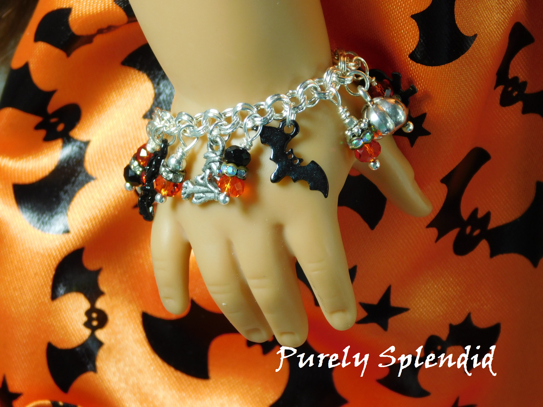 Halloween Charm Bracelet with pumpkin, bat, flying witch and sparkling charms shown on an American Girl Doll