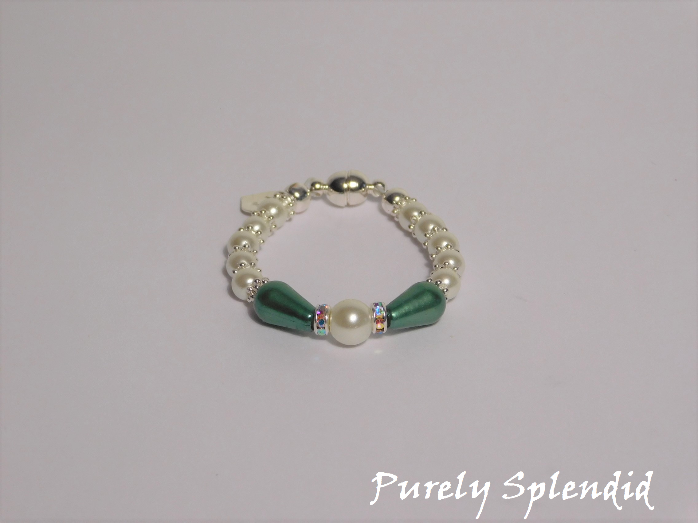 round white pearls with silver spacer beads with the main focus made up of one large white pearl bead surrounded by a thin sparkling bead and green pear shaped pearl 