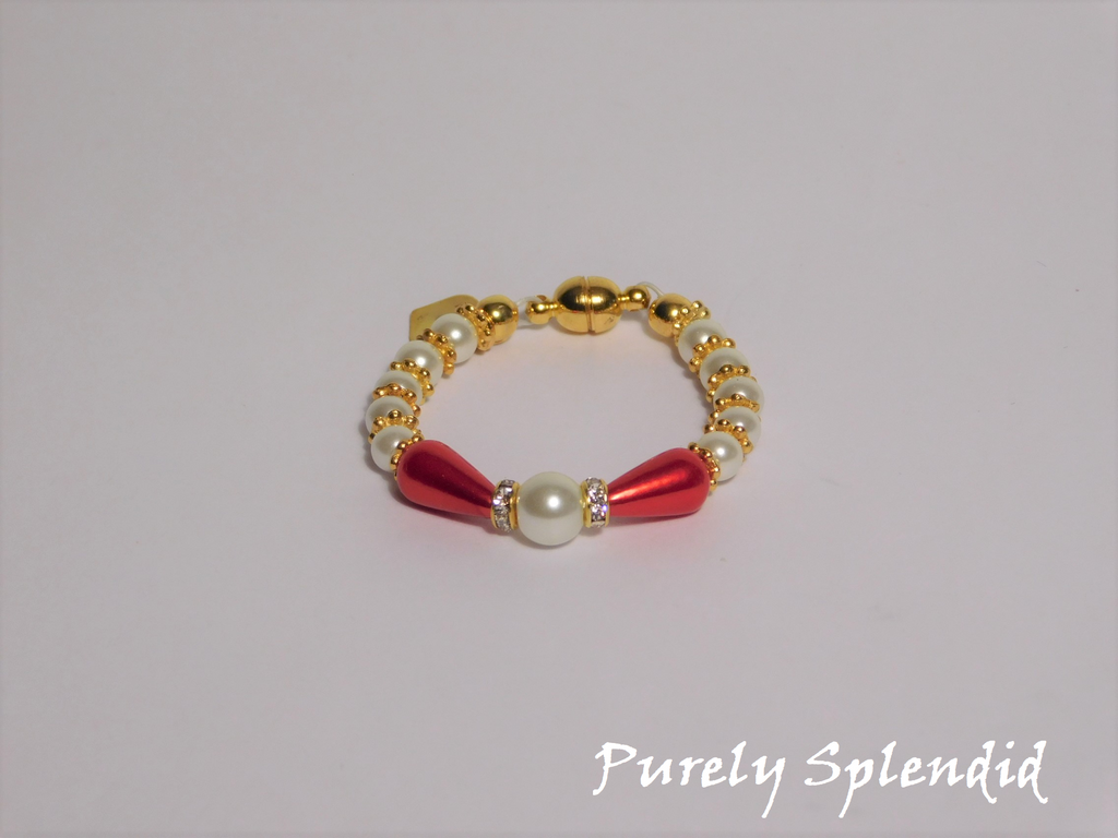 round white pearls with gold spacer beads with the main focus made up of one large white pearl bead surrounded by a thin sparkling bead and red pear shaped pearl 