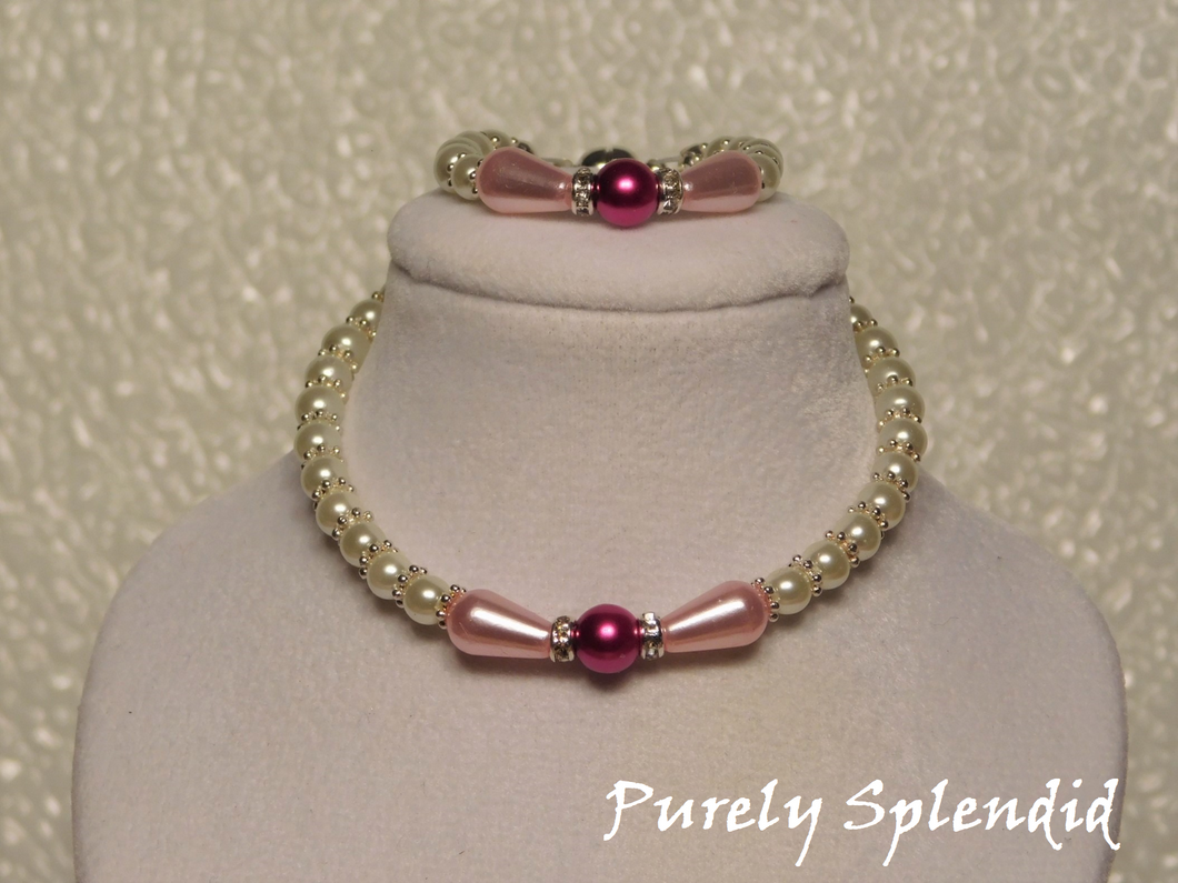 Beautiful dark pink pearl surrounded by light pink teardrop pearls is the focal point of this white pearl neckace and bracelet