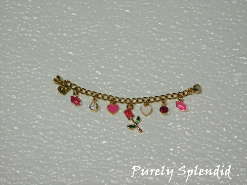 seven charms on a gold chain. red lips, crystal, pink heart, red rose on a stem, white heart, red crystal and pink lips.