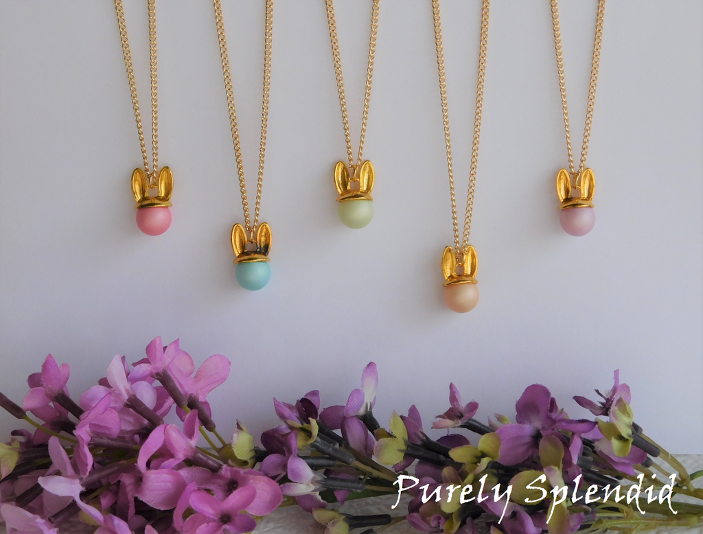 Five Pastel colored round beads with gold colored bunny ears on a long gold colored chain