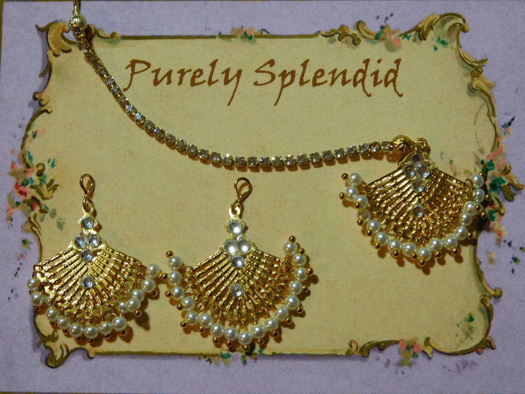 Beautiful gold fan shapes with multiple tiny pearl like beads hanging. Maang Tikka has a sparkling gold hair chain. Shown with matching earrings
