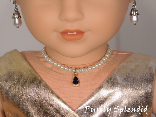 18 inch doll shown all dressed up wearing a string of white pearls with a sparkling blue center pendant