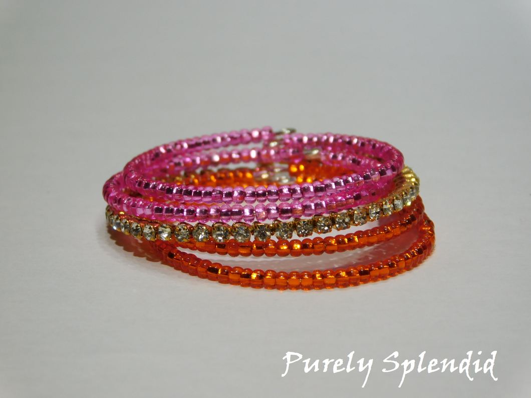 two pink and two orange stacking bracelets as well as one sparkling gold stacking bracelet