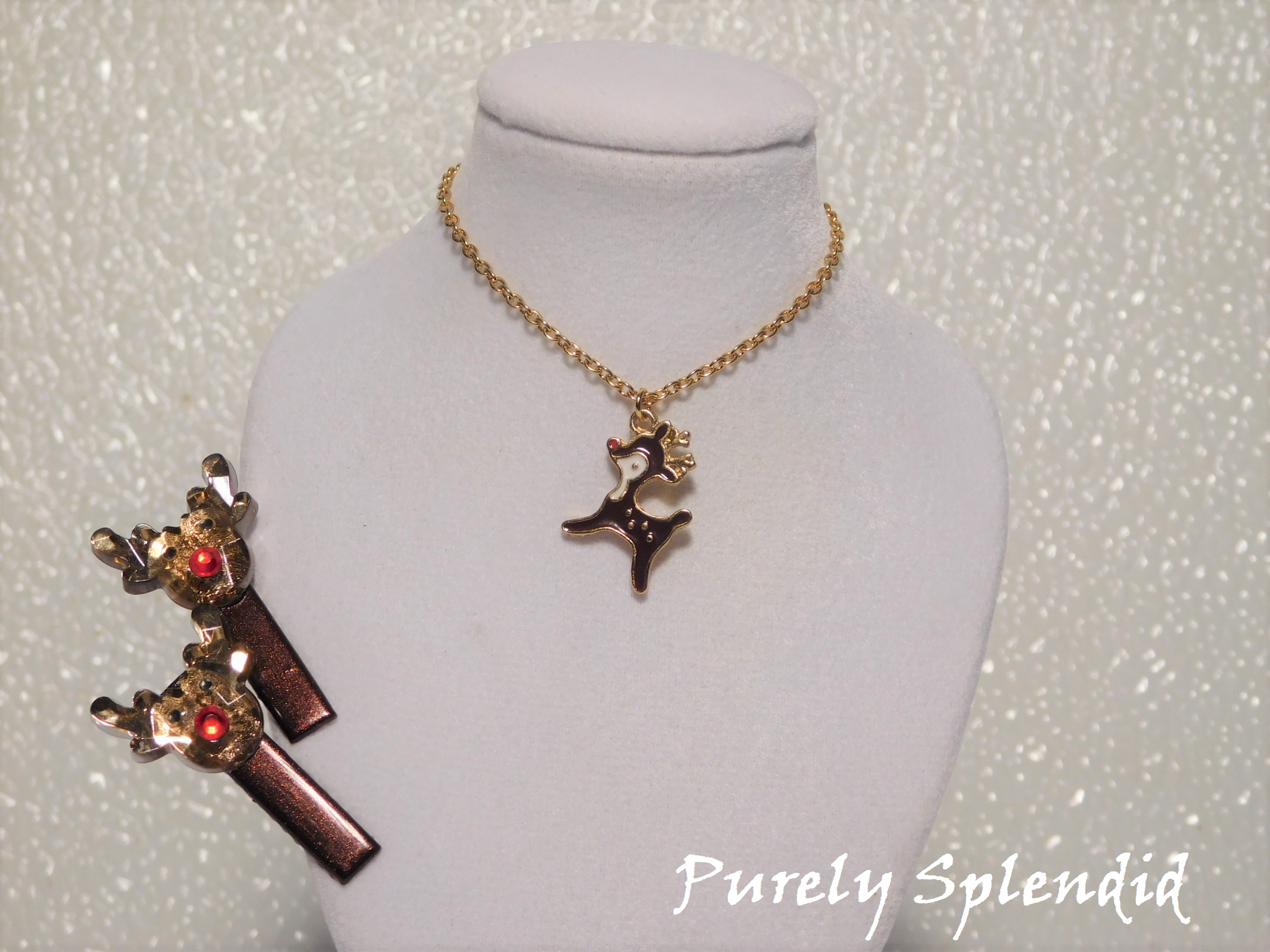 Two brown hair clips each with a 3D Rudolph Reindeer head and a full body brown and white Rudolph Reindeer charm on a gold chain necklace shown on a white background