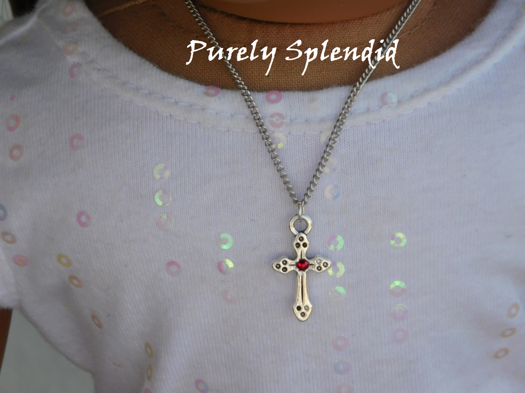 Decorative Silver Cross with a sparkling red center crystal hanging on a silver chain around an 18 inch dolls neck