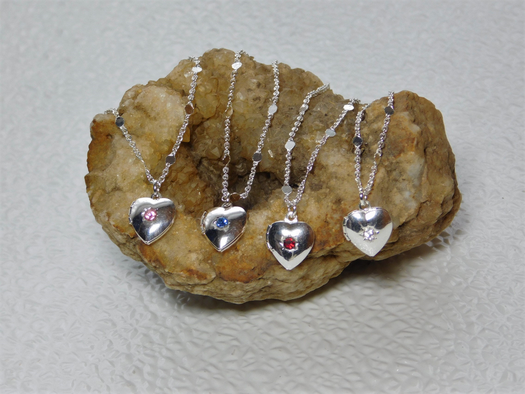 Four Silver Heart Lockets shown - each with a different center stone, pink, blue, red and crystal on a pretty silver chain