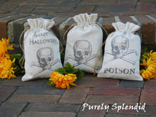 Load image into Gallery viewer, Three Skull Halloween Fabric Gift Bags shown- each with a skull and crossbones, one only with skull and crossbones, one with the words Happy Halloween and one with the words Poison
