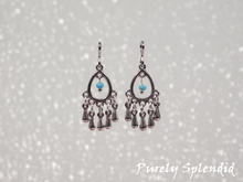 Load image into Gallery viewer, Silver colored open teardrop shaped earrings with five silver colored drops hanging below and one blue colored bead hanging in the center of the teardrop.
