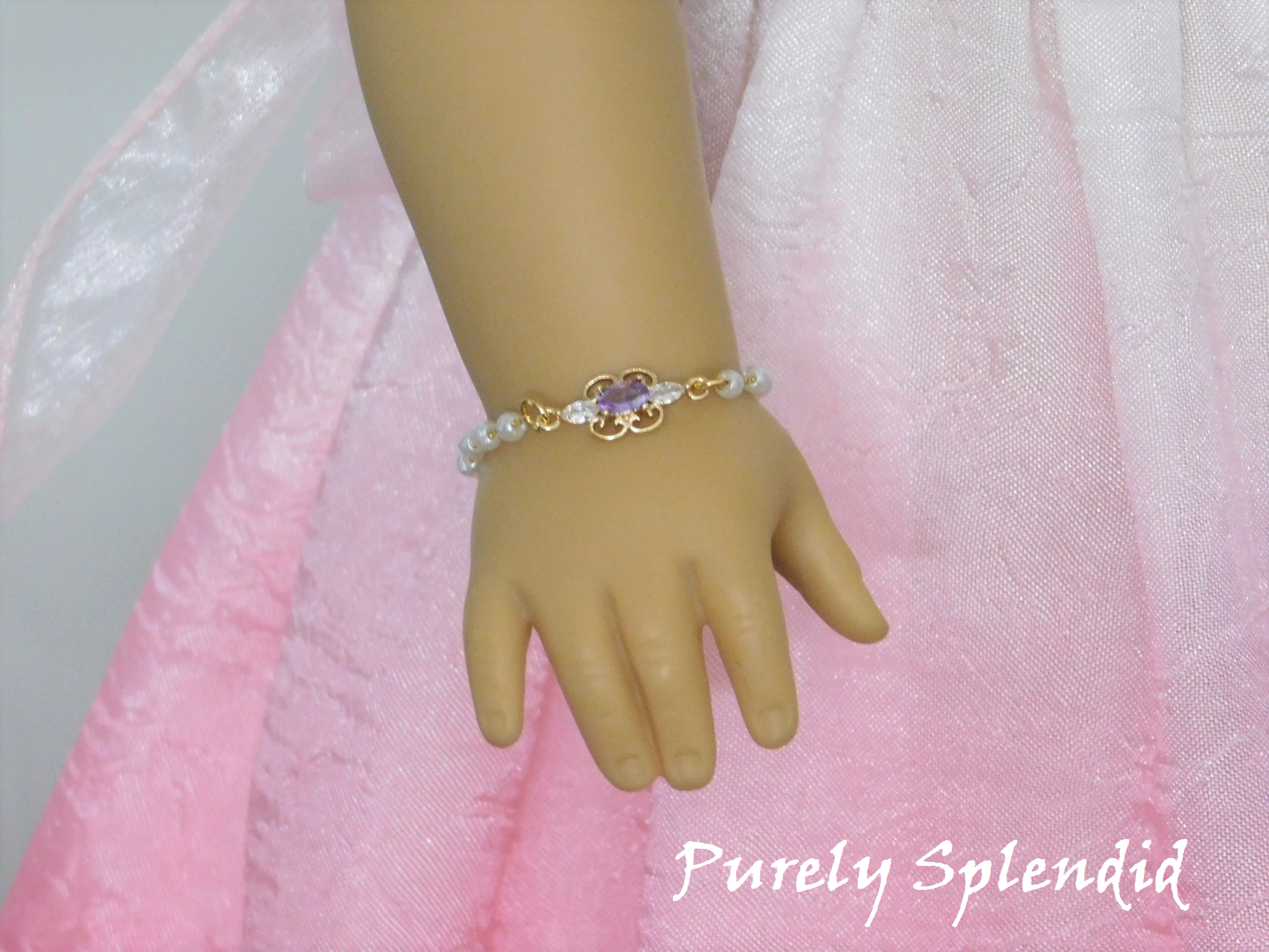 Dainty pearl like beaded chain with a focal point of a cubic zirconia lavender and crystal pendant shown on an 18 inch doll