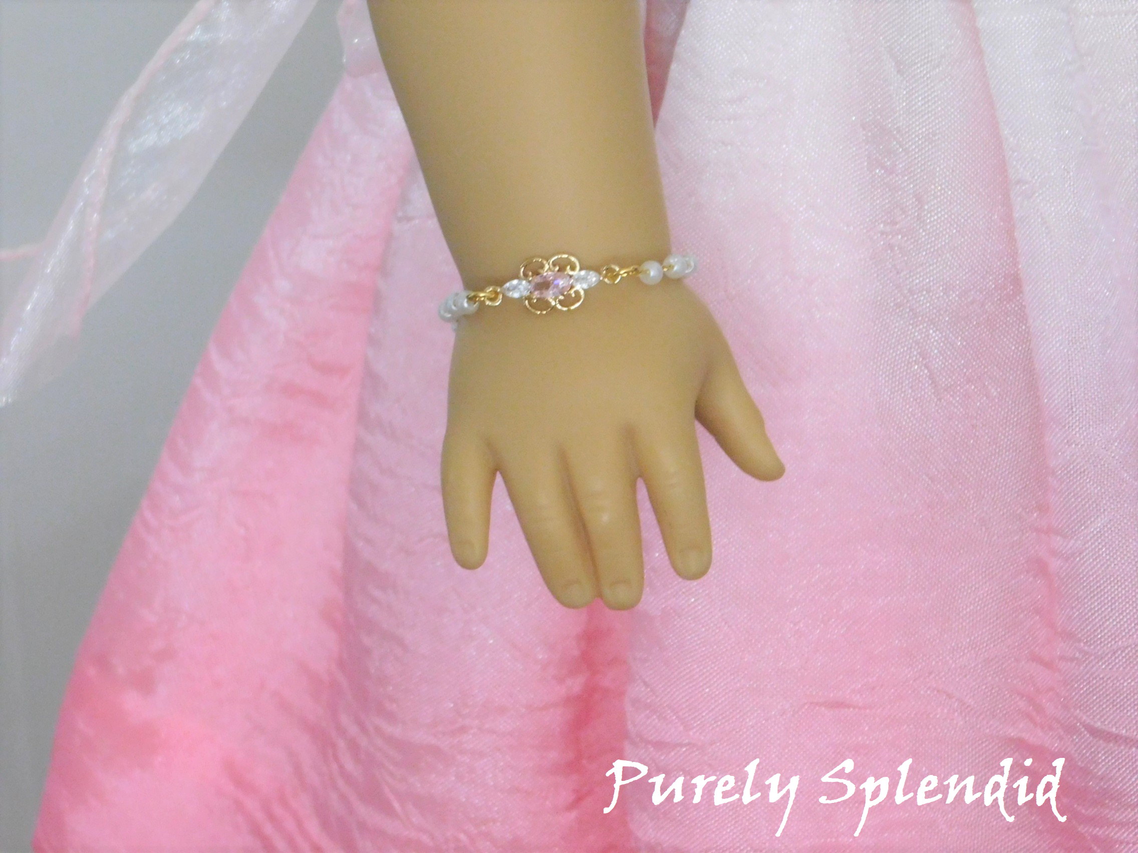 Dainty pearl like beaded chain with a focal point of a cubic zirconia pale pink and crystal pendant shown on an 18 inch doll