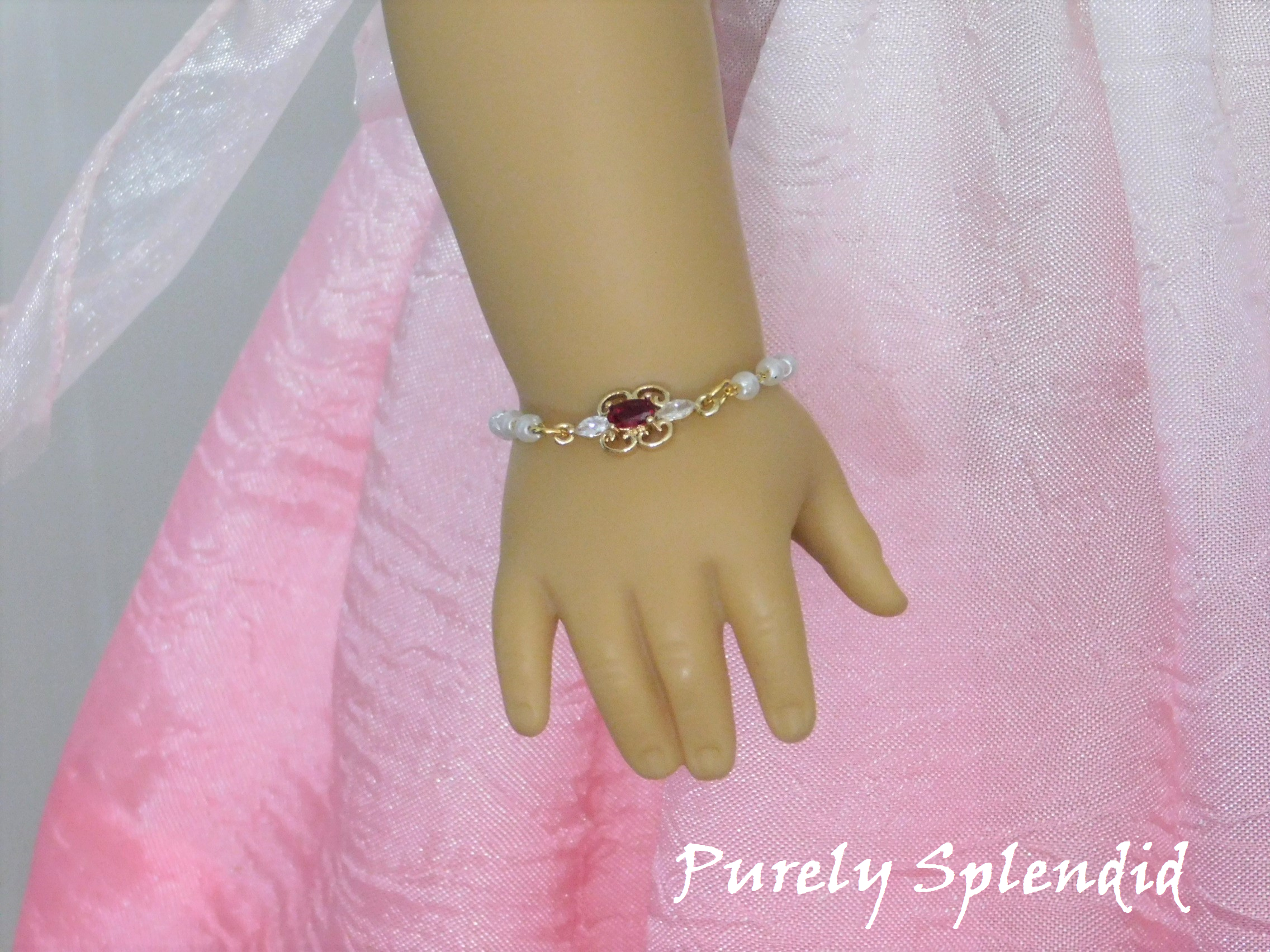 Dainty pearl like beaded chain with a focal point of a cubic zirconia red and crystal pendant shown on an 18 inch doll