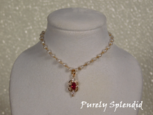 Load image into Gallery viewer, Dainty pearl like beads are part of a gold chain. Focal point is a Ruby cubic zirconia pendant hanging from the pearl chain.
