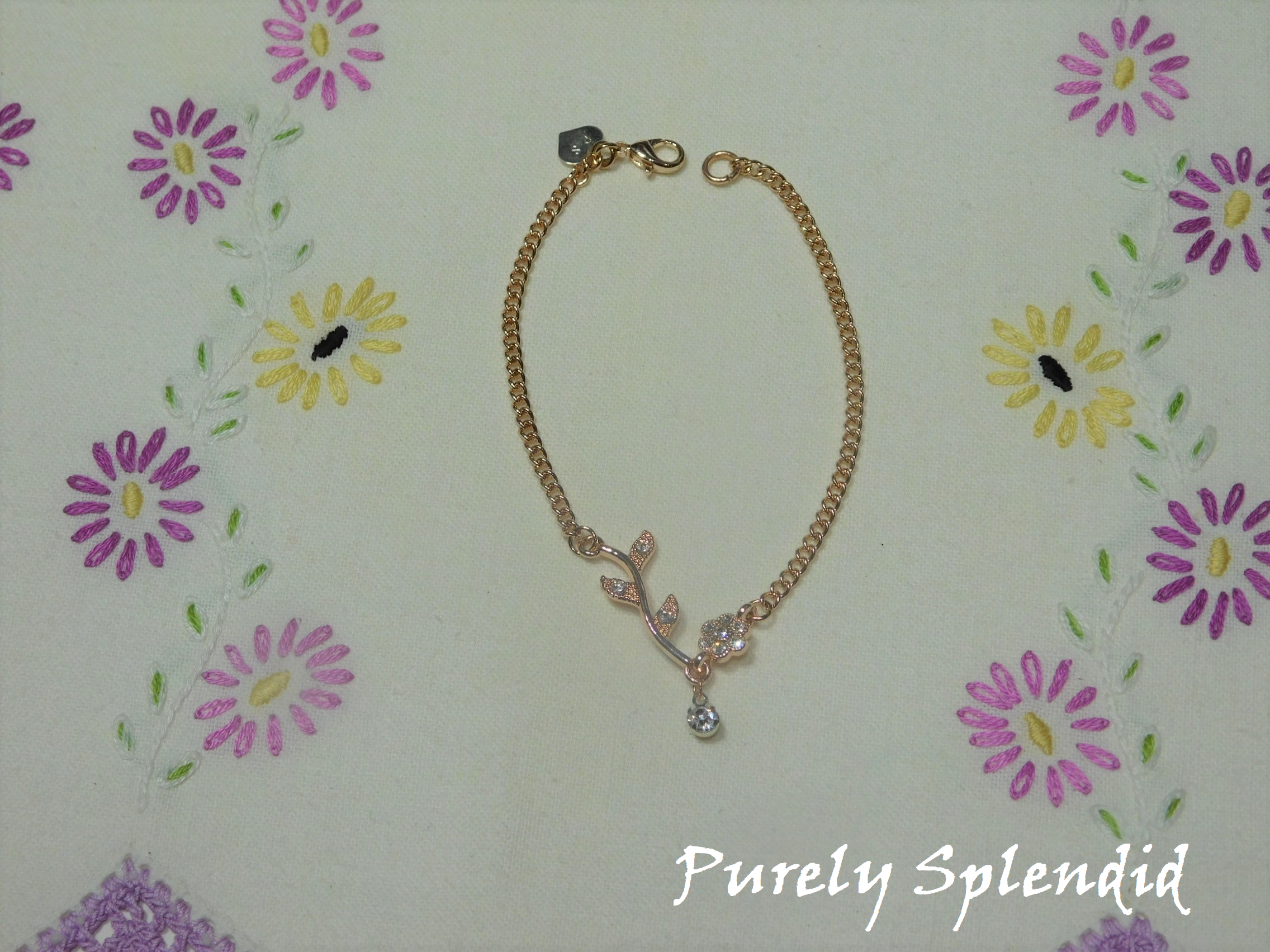 Sparkling Rose Gold Falling Flower Necklace shown laying on a white floral background