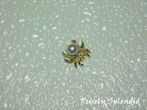 A large faux pearl is the body of this golden spider brooch