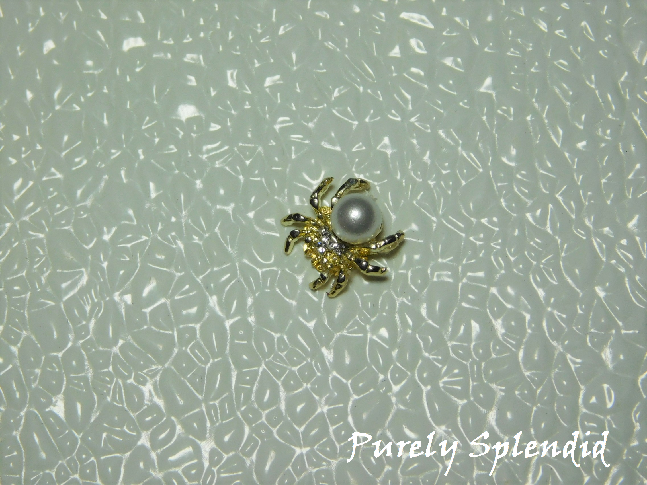 A large faux pearl is the body of this Spider Brooch