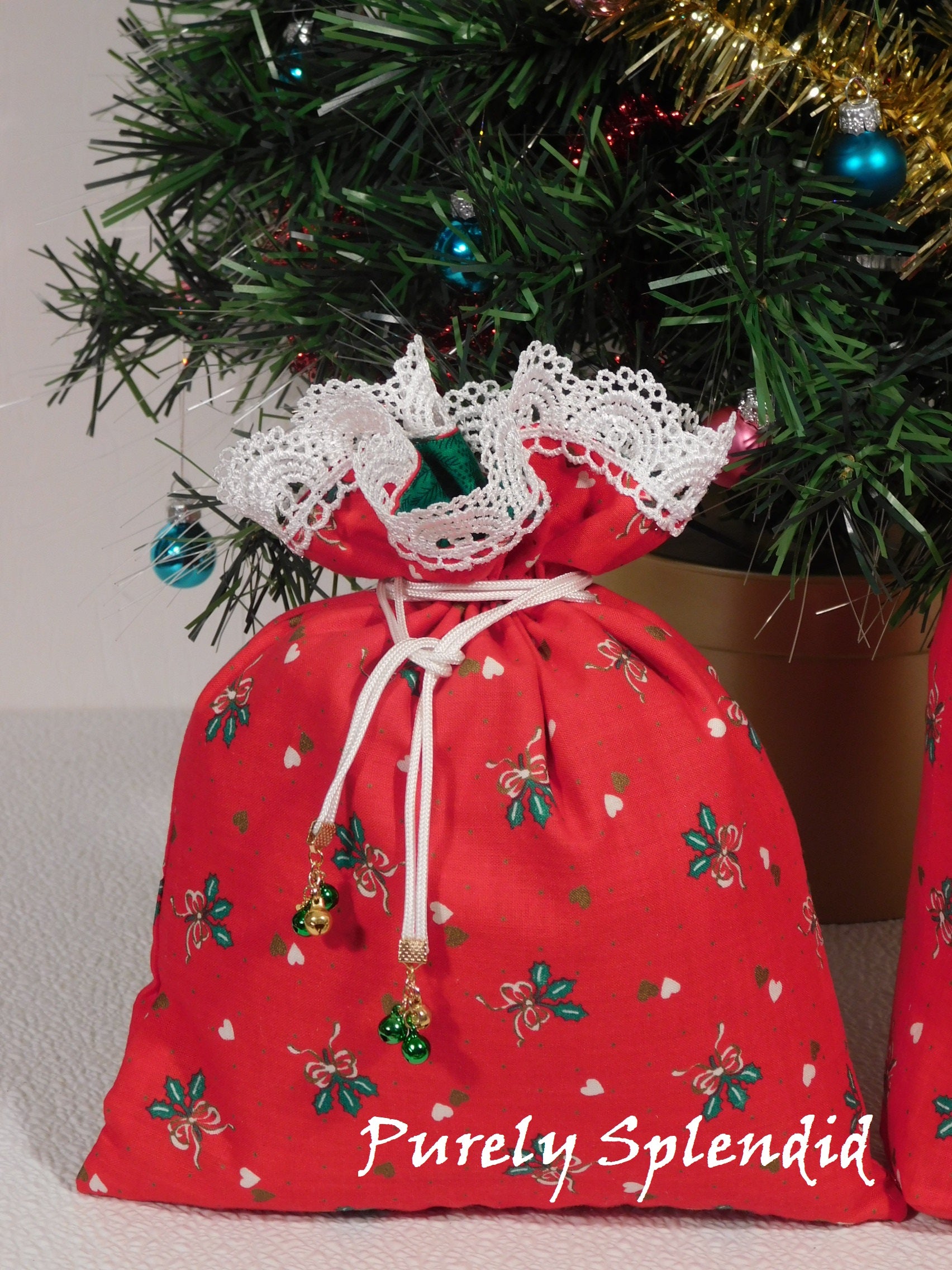 small red fabric gift bag with white lace and jingle bell drawstrings